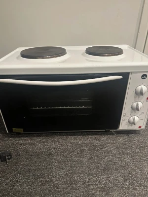 Vit minispis med ugn från Wilfa - Säljer en vit minispis från Wilfa med två kokplattor och inbyggd ugn. Spisen har vred för temperatur och funktioner samt en svart glaslucka. Perfekt för mindre kök eller studentboende. Kompakt och smidig design i metall och glas.