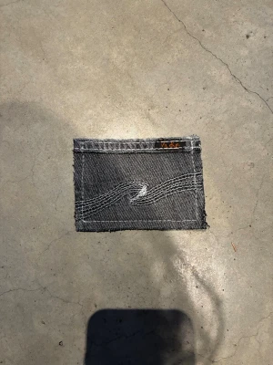 Jeansplånbok - Minimalistisk cardholder i grå denim från Nudie Jeans. Plånboken har råa kanter, kontrastsömmar och en liten Nudie Jeans-lapp i hörnet. Perfekt för kort och sedlar, med unik look tack vare återvunnet jeanstyg.