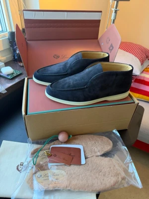 Svarta mocka loafers från Loro Piana - Säljer ett par stilrena svarta loafers från Loro Piana, modell Winter Walk. Skorna är i mjuk mocka med ljus sula och har en klassisk, minimalistisk design. Insidan är beige och de kommer med extra innersulor och originalkartong. Storlek 41 . Finns i Göteborg eller frakt via PostNord 