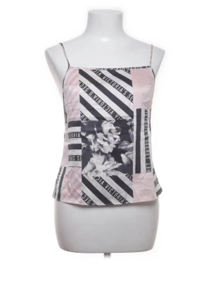 Mönstrad linnetopp från Victoria's Secret - Trendig linnetopp från Victoria's Secret med smala axelband. Toppen har ett patchwork-mönster i svart, vitt och ljusrosa med både blommor och textdetaljer. Tillverkad i ett mjukt, glansigt material som känns lyxigt mot huden. Perfekt för dig som vill sticka ut.