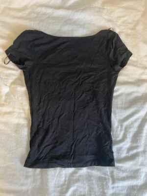 Mörkgrå tight topp med öppen rygg - Mörkgrå, tight topp med korta ärmar och en djup, öppen rygg. Knappt använd, som ny.