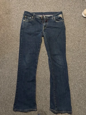 Mörkblå Replay bootcut jeans  - Snygga mörkblå bootcut jeans med kontrastsömmar och broderade detaljer på bakfickorna. Tillverkade i mjuk denim som ger en skön passform. Storlek: W31, L34. 