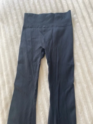 Mörkgrå ribbade utsvängda träningsbyxor  - Snygga mörkgrå leggings med ribbad struktur och utsvängda ben. Hög midja för en bekväm passform. Materialet är stretchigt.