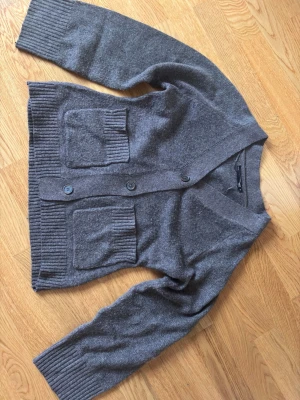 Kofta från lager 157 - Mysig gråbrun kofta med två stora ribbstickade fickor framtill och knäppning med tre knappar. Koftan har breda ribbade muddar vid ärmslut och nederkant samt en djup V-ringning. Perfekt för lager-på-lager och chill dagar. Använd en gång. Sälj då den bara tar upp plats i min garderob men har haft sen i vintras. 💕😊