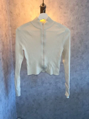 Beige ribbad ziptröja🫶🏻 - Trendig beige ribbad tröja med dragkedja framtill och hög krage. Croppad modell med långa ärmar🙌🏻