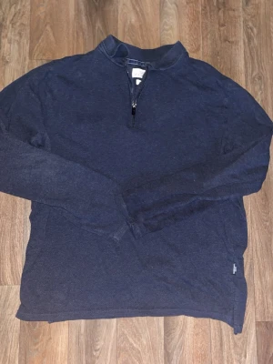 Mörkblå halvzip tröja - Mörkblå långärmad tröja med halv dragkedja framtill och ståkrage. Tröjan har en enkel och stilren design, perfekt för lager på lager. Tillverkad i mjukt material som känns skönt mot huden.