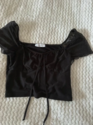 Svart blus med fina detaljer - Fin svart blus med genomskinliga puffiga ärmar. Den är köpt på ALCOTT i storlek S. 🌸 Aldrig använts. 🌺