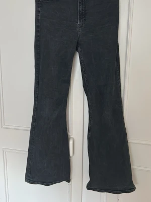 Svarta high waist jeans - Säljer ett par svarta high waist jeans med lätt tvättad look och utsvängda ben. Jeansen har klassisk femficksdesign och synliga sömmar. Perfekta för dig som gillar retrostil och vill ha ett par jeans som sticker ut.