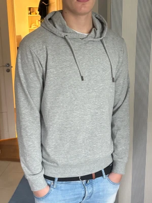Ljusgrå hoodie - Snygg ljusgrå hoodie i väldigt skönt material. Perfekt för en avslappnad stil. Tröjan är knappt använda heller, utan är som ny. 