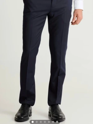 Mörkblå kostymbyxor med pressveck - Snygga mörkblå kostymbyxor med klassiskt rakt snitt och tydliga pressveck. Byxorna har en stilren design och passar perfekt till skjorta eller kavaj. Perfekt till student eller skolavslutning 