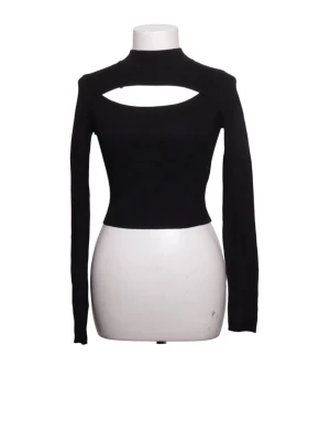 Svart långärmad topp med cut-out - Trendig svart långärmad topp med hög hals och snygg cut-out detalj över bröstet. Figurnära passform och croppad längd, perfekt att styla med höga jeans eller kjol.