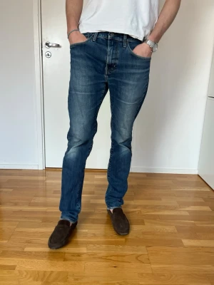 Blå raka jeans med slitningar - Snygga blå jeans med raka ben och diskreta slitningar på låren och knäna. Jeansen har klassisk femficksdesign och normal midja. Perfekta för en avslappnad och trendig look. Materialet är denim i bomull.
