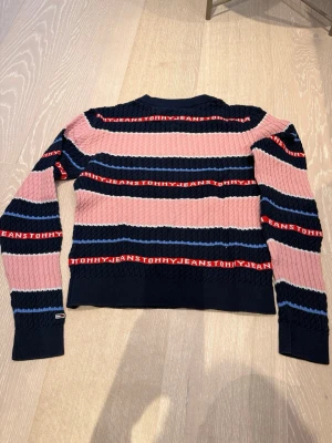 Stickad tröja Tommy Jeans - Snygg stickad tröja från Tommy Jeans. Tröjan har rund hals, långa ärmar och ribbade muddar. Perfekt för dig som gillar färg och mönster!