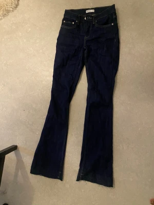 Mörkblå botcut jeans  - Super snygga utsvängda lågmidjade jeans från Gina! Använda endast en gång och i relativt bra skick. Ny pris var 499 kr!! Obs! Jag har sprättat upp där nere och skulle stryka dem så fastnade något på jeansen genom strykjärnet därav de låga priset men går säkert att få bort. Skriv för bild!❤️