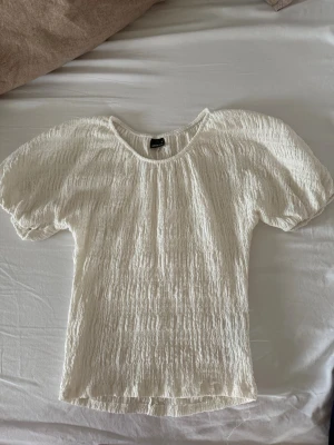 Vit puffärmad blus Gina Tricot - Supersöt vit blus från Gina Tricot med puffärmar och smockad struktur. Blusen har rund halsringning och är gjord i ett lätt, luftigt material som känns perfekt för varmare dagar. Enkel att styla till både jeans och kjol. Endast använd ett fåtal gånger så ser ut som ny! Skicka dm ifall ni har fler frågor ! Köparen står för frakten 💕.