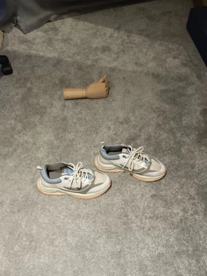 Chunky sneakers från Cleens i grått - Snygga chunky sneakers från Cleens i grått och vitt med detaljer i ljusblått mesh och beige. Skorna har en kraftig sula i vitt och orange, samt coola paneler och snörning framtill. Perfekta för dig som gillar streetstyle och sportig vibe.