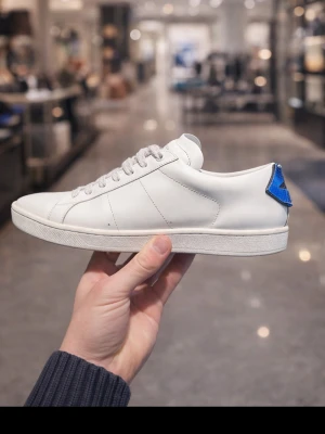 Saint Laurent skor  - Säljer ett par nästan HELT NYA, saint lauren skor | storlek 41 | färg vita med blå och röd detalj vid hälen | skick 9/10 | NY PRIS 6500kr Mitt pris 1299🤩🤩🤩. Bara att skriva för eventuella frågor. 
