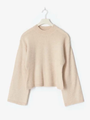Beige stickad tröja med vida ärmar - Mysig beige stickad tröja med rund halsringning och vida ärmar. Tröjan har en rak, något kortare passform och är tillverkad i ett mjukt material som känns skönt mot huden. Perfekt att matcha med jeans för en avslappnad look.