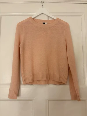 Ljusrosa stickad tröja H&M - Mysig ljusrosa stickad tröja från H&M med rund halsringning och långa ärmar. Tröjan har ribbade muddar vid ärmslut och nederkant, samt en enkel och stilren design som passar till det mesta. Lite nopprig 
