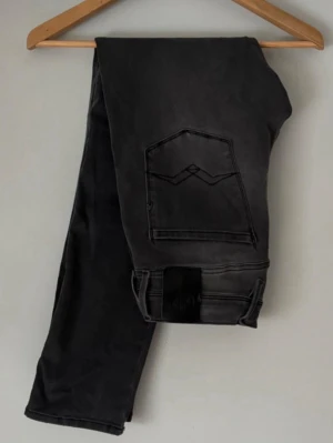 Svarta Replay jeans  - W29-L30 Säljer ett par svarta jeans från Replay med snygg tvättad finish och klassisk femficksmodell. Jeansen har raka ben och detaljerade sömmar på bakfickorna. Perfekta för dig som gillar en stilren men avslappnad look.