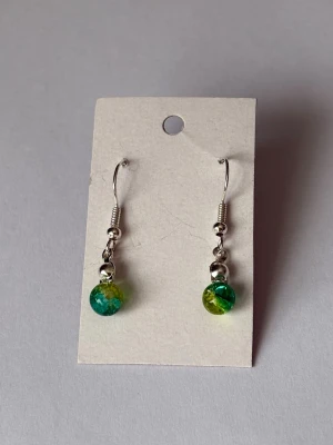 Gröna pärlörhängen - Söta örhängen med silverfärgade krokar och detaljer.                                                                 Pärlan är grön-ljusgrön. 💫                                Örhängerna är självklart helt oanvända och de är nickelfria.                                                                    De sitter på en bit kartong för att enklare kunna visa hur de ser ut.                                                     Ha det fint!🌻