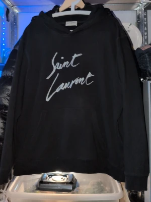 Saint Laurent hoddie  - Säljer min saint Laurent hoddie då den inte kommer till användning längre den är i XL men sitter bättre på L skulle jag ändå säga jag är 185 på bilden. Inga skador då jag vart försiktigt med den vet ej om äkta så säljer ganska billigt. bara att höra av er vid funderingar. Mvh Elias...