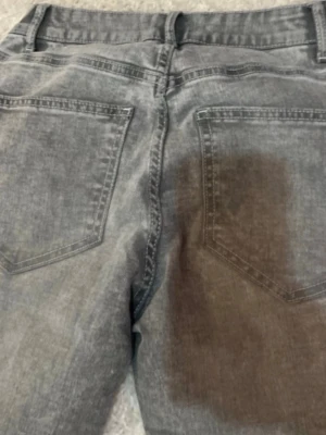 Grå tvättade jeans med raka ben - Säljer ett par grå jeans med tvättad look utsvängda ben. Jeansen har klassiska bakfickor och normal midja. Materialet är denim i bomull och de har en avslappnad passform som funkar till många stilar.