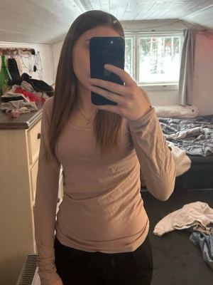 Ljusrosa långärmad topp - En stilren ljusrosa långärmad topp med rund halsringning. Toppen har en slim passform och är tillverkad i ett mjukt material som sitter skönt mot kroppen. Perfekt att matcha med jeans eller kjol för en enkel och snygg look.