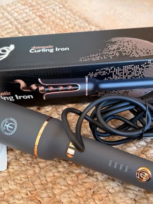 Automatisk locktång med display - Snygg automatisk locktång i matt svart med guldiga detaljer och digital display för temperaturinställning. Ergonomiskt handtag och lång sladd gör den smidig att använda. Perfekt för att skapa snygga lockar snabbt och enkelt. Endast provad nypris 699kr 