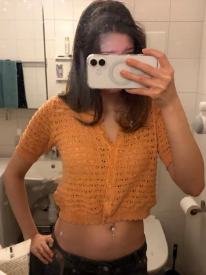 Kort orange stickad kofta från Desigual - Superfin kortärmad stickad kofta i orange från Indiska. Koftan har knappar framtill och ett luftigt, virkat mönster. Perfekt att styla över ett linne eller klänning. Materialet känns lätt.