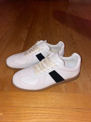  Vita Maison Margiela Gats - Säljer dessa snygga, vita Maison margiela gats med svart detalj. Dem är helt nya och oandvända, bara provade. Perfekta nu till våren och sommaren.