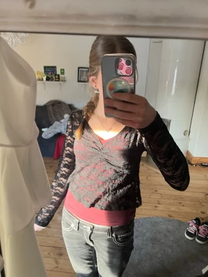 Svart spetsblus med v-ringning - Säljer en svart långärmad blus i spets med v-ringning och figurnära passform. Blusen är genomskinlig och har ett snyggt mönster i spetsen, perfekt att styla över ett linne eller topp. Supersnygg till både jeans och kjol!