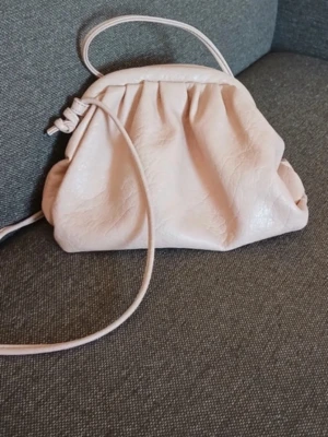 Ljusrosa axelremsväska dumpling - Söt ljusrosa handväska med axelrem och mjuk, rynkad design. Bra skick och postar snabbt!!❤️❤️