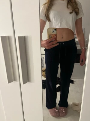 Mörkblå mjukisbyxor med fickor - Mörkblåa Juicy Couture byxor i storlek S. Använda till och från men så gott som nya förutom ena metalldetaljen på ena snöret som är av. Skriv privat för fler bilder eller frågor om plagget.