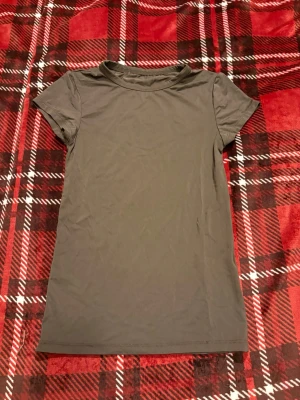 Mörkbrun basic t-shirt - En enkel och stilren mörkbrun t-shirt med rund hals och korta ärmar. Perfekt till jeans eller shorts för en avslappnad look. Tillverkad i 90% polyamid och 10% Elastan som känns skön mot huden.