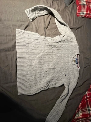 Ljusgrå kabelstickad tröja Polo Ralph Lauren - Kabelstickad ljusgrå tröja från Polo Ralph Lauren med rund halsringning och diskret broderad logga på bröstet. Den är 100% äkta köpt i New York på ett shopping center då jag köpte den för cirka 115 dollar mitt pris 500 passar 10 till 12 år gammal. Hör av er vid intressen