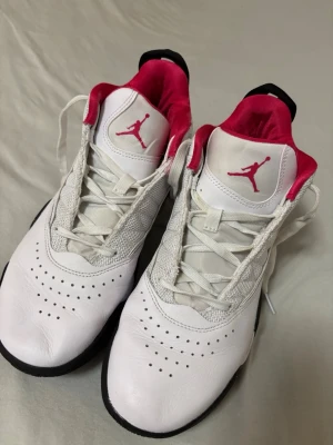 Vita Air Jordan stay basketskor - Säljer ett par vita Air Jordan stay basketskor med svart sula och rosa insida. Skorna är i bra skick och har inga defekter som påverkar användningen. De har kommit till användning och har tvättats, det ända märkvärdiga är att printen som ska vara i sulan suddats ut med tiden och den andra fotens sula där det ska stå ”jump” på har halvt suddats ut! 💕 Är själv en strl 39 men 41 passade mig bra! 