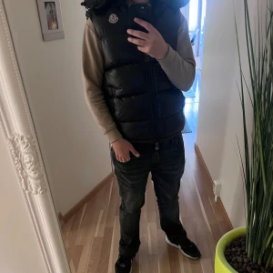Moncler Väst - DEN SOM KÖPER FÅR MED SIG EN MYSTERY PLAGG!                                                                 Snygg svart dunväst med glansig finish. Den har varit använd av mig men har tagits hand om till högst nivå. NFC funkar ej eftersom att den är tvättad men skan finns och dist lappen, använt den under typ 1-2 månaders totaltid Äktenhet kan ej garanteras