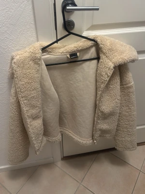 Beige teddyjacka  - Jättefin teddyjacka från gina tricot i storlek S. Är köpt för några år sen så rätt gammal, men superbra skick och väl omhändertagen. Finns en liten fläck på insidan av jackan som inte gått bort i tvätten men syns inte när man har på jackan. Säljer eftersom den är för liten.