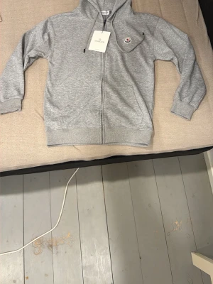 Grå zip hoodie från Moncler - Snygg grå hoodie från Moncler med dragkedja framtill och huva. Sprillans ny inte använd en enda gång. 