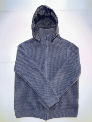 Mörkblå stickad cardigan jacka - Säljer en mörkblå cardigan från polo club med dragkedja framtill och en vadderad huva. Tröjan har grovstickad struktur och ribbade muddar vid ärmslut och nederkant. Perfekt för kyliga dagar och enkel att matcha med jeans eller byxor. Storlek L (passar även M). Skick 9/10.