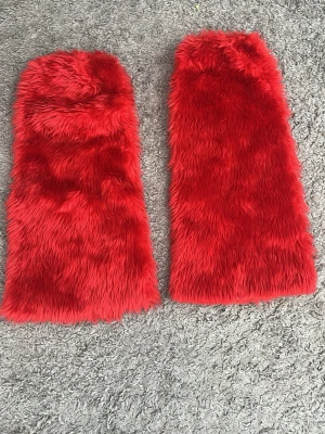Fluffiga benvärmare m resår upptill. - Fluffiga benvärmare i fin röd färg. Längd ca 59 cm. Helt nya.