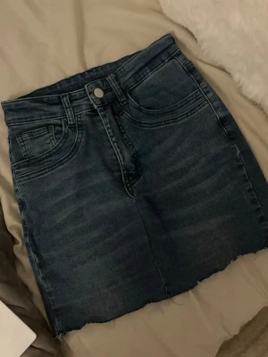 Mörkblå jeanskjol-hemmasydd - Hemmasydd kjol av ett par jeans. Mjukt matreal, stretchit, ett litet hål man bara kan sy ihop snabbt man kan även klippa den kortare om man skulle vilja det. Men kan ju även göra slitningar elelr annat med den också. Pris kan diskuteras (lite grann)