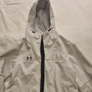 Jacka Under armour  - Jacka Under armour. Inga byten. Ljusa fläckar på vänster sida vid krage och axel. Se bilder.