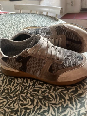 Grå vita rockrunners - Snygga sneakers i grått med mesh-ovandel och detaljer i mocka. Skorna har vita snören och en brun sula. Perfekta för dig som gillar en stilren look. Diskret mönster på sidorna och bekväm passform. 