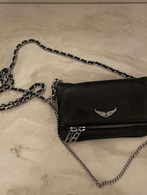 Svart axelväska med kedjerem - Snygg svart axelväska i läder  med silverfärgade detaljer. 
