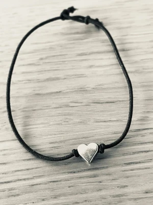 By prisförslag- 1 st Svart armband justerbart med hjärta - Snyggt och enkelt armband med svart justerbart band och ett silverfärgat hjärta i metall som detalj. Perfekt för dig som gillar minimalistisk stil och vill ha något diskret men ändå personligt.
