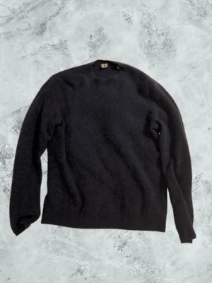 Mörkblå stickad tröja i ullmix - Mysig mörkblå stickad tröja med rund hals och långa ärmar. Tröjan är i en mjuk ullmix och har en klassisk, enkel design som passar perfekt till jeans eller kjol. Ribbstickade muddar vid ärmslut och nederkant ger en snygg finish.