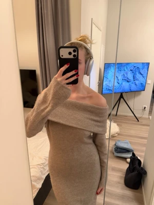 Beige offshoulder stickad klänning - Säljer en beige stickad långklänning med offshoulder-design och långa ärmar. Klänningen har en bred krage som vilar över axlarna och ger en snygg och trendig look. Perfekt för dig som vill ha något både bekvämt och stilrent.