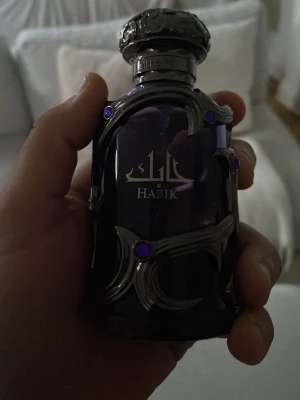 Habik - byte - Elegant parfymflaska från Habik i mörklila glas med dekorativa silverfärgade metallinslag och lila stenar. Flaskan har en unik, lyxig design och orientaliska inslag, perfekt som statement på parfymhyllan.